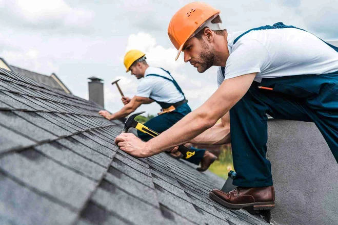 selective focus of handsome handyman repairing roof with coworker