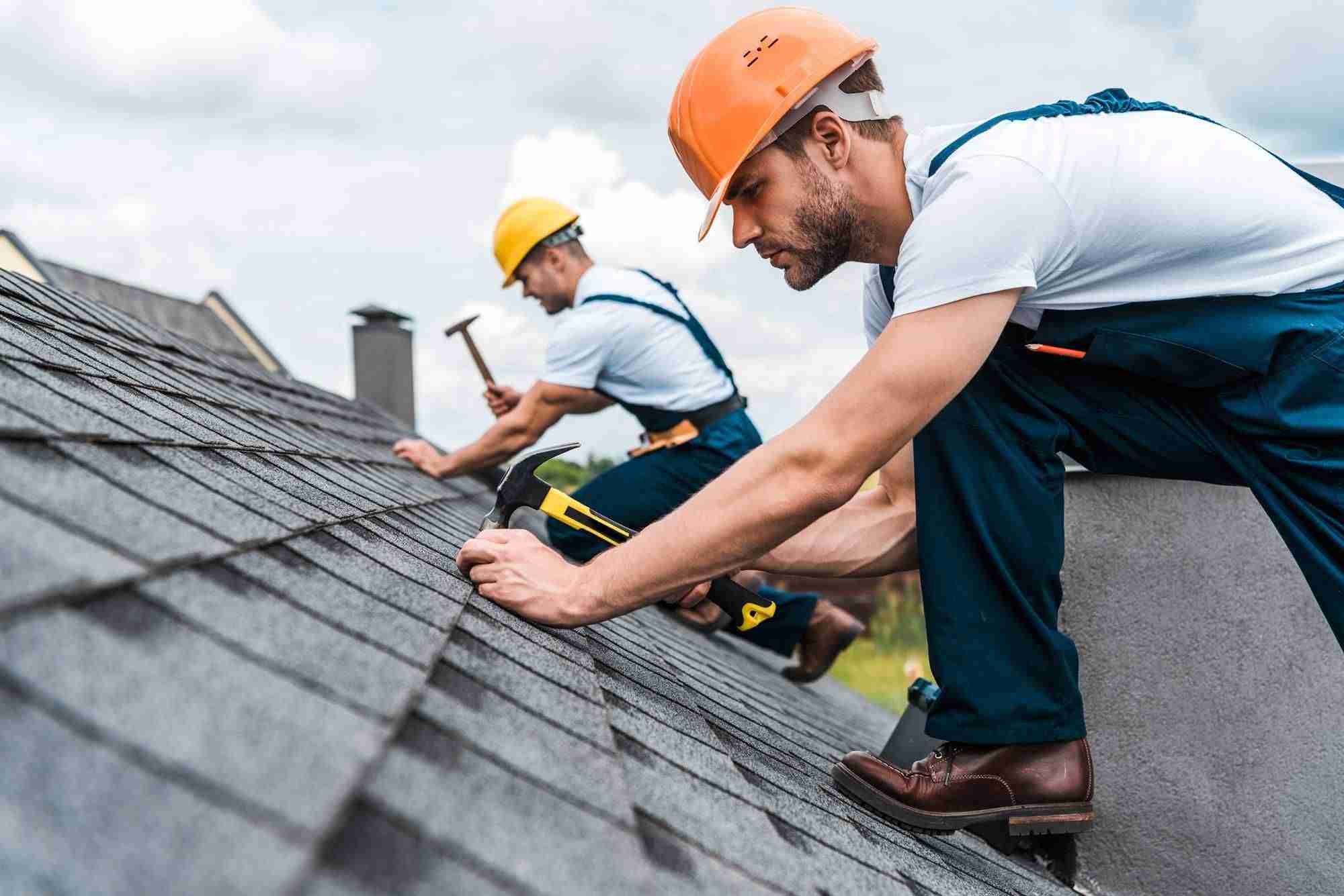 selective focus of handsome handyman repairing roof with coworker
